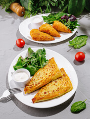Savory dishes featuring stuffed pastries and fresh salad on a bright table