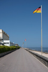 Saint-Aubin-Sur-Mer, France - 08 10 2025:  View of the the jetty with many country flags and people walking on away