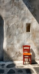 Orange chair bathed in sunlight against weathered wall