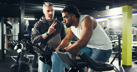 Exercise bike, man and coach in gym for fitness, help or workout for health. Cycling, personal...
