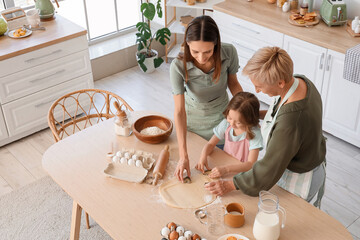 Little girl with her mother and granny making cookies in kitchen
