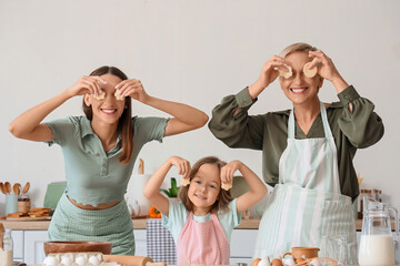 Cute little girl with her mother and granny making cookies in kitchen