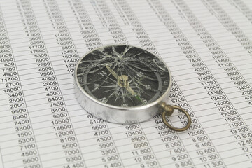 Broken compass on financial paper close up.