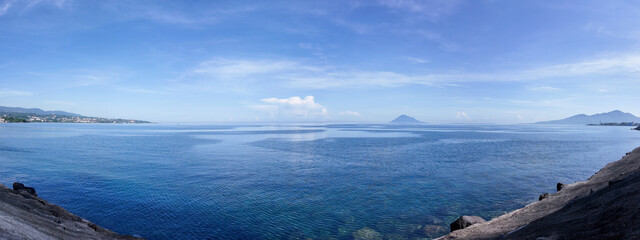A calm blue ocean panorama with distant mountains under a clear sky