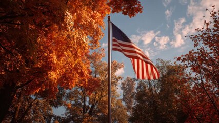 American flag waving proudly in the autumn wind, with vibrant foliage and a blue sky as backdrop - Powered by Adobe
