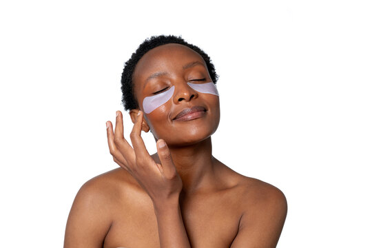 Woman applying skincare patches while enjoying a moment of relaxation at home during a self-care session in the afternoon light