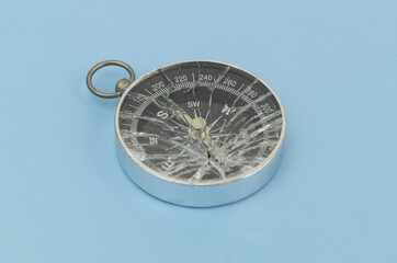 Broken compass on blue background. Lost direction, navigation and wrong way concept.