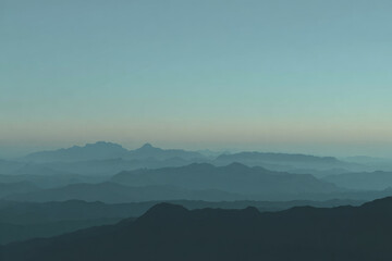 Serene mountain landscape with layered silhouettes, soft blue gradient sky, tranquil atmosphere, and distant peaks fading into mist, perfect for calm and peaceful nature backgrounds