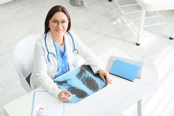 Female doctor with x-ray image of lungs at table in clinic