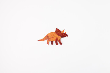Obraz premium Triceratops made of autumn leaves symbolizing creativity, eco design, and nature art, ideal for education, children publishing, seasonal marketing, environmental campaigns, and DIY brands,