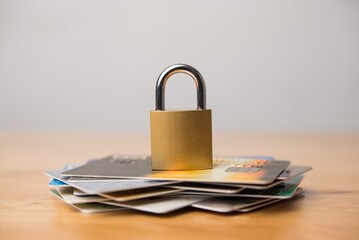 Padlock on stack credit cards on wooden table with white wall background. Use credit cards...