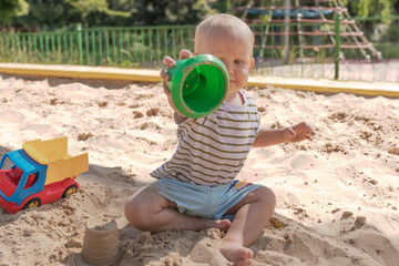 Baby boy playing in sandbox, little funny European boy, blond 1.5 years old, having fun on...