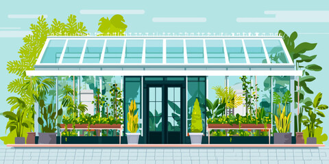Modern glass greenhouse facade with a white frame, filled with lush tropical plants and foliage.