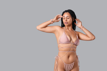Pretty young African-American woman in bikini with accessories on white background