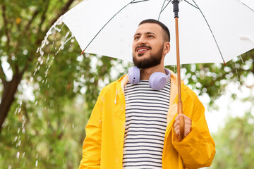 Young man with yellow raincoat and umbrella in park