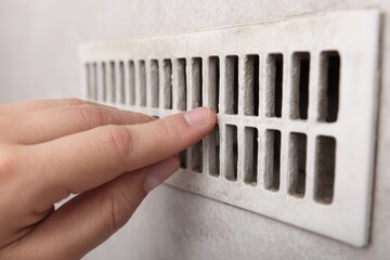 Dirty Air Duct Clean. Close up of Dusty Ventilation Grille and Hand Removing Dust Particles