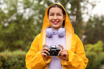 Young woman with yellow raincoat and photo camera in park