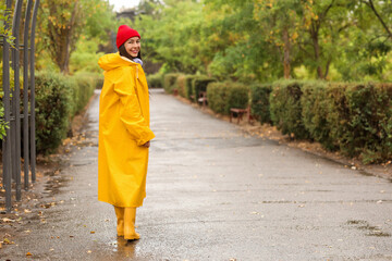 Young woman with hat and yellow raincoat in park