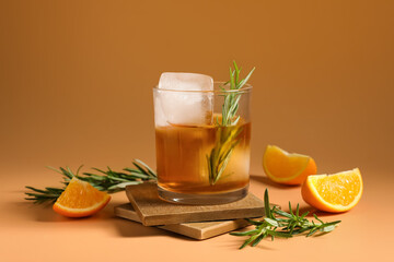 Glass of tasty Old Fashioned cocktail with rosemary on brown background