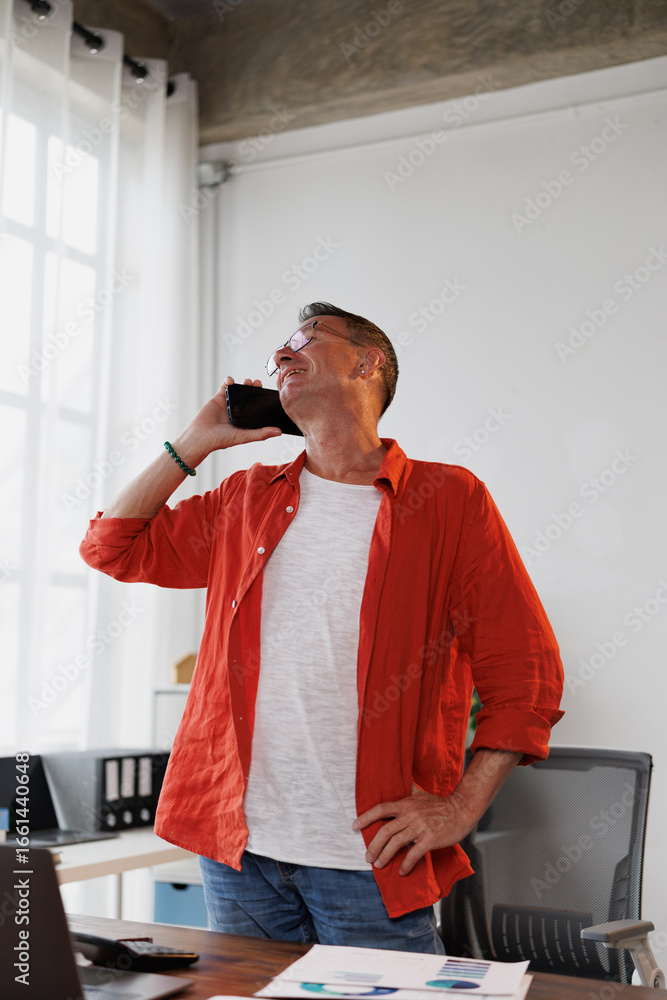 Poster senior manager standing at his desk talking on the phone with a satisfied expression, discussing bus