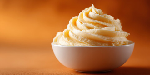 Creamy whipped mashed potatoes in white bowl on orange background