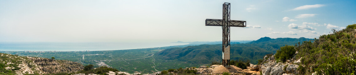 Panoramic view. Big cross in the peak of a mountain, in Tavernes de la Valldigna, (Spain) 