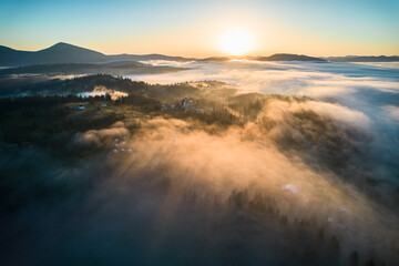 Stunning aerial view of sunrise over mountainous landscape, with thick fog blanketing valleys and...