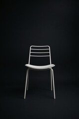 Studio portrait of a stylish white chair with clean lines isolated on a stark black background, representing modern furniture design