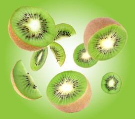 Fototapeta premium Cut fresh kiwi fruits swirling in air against green gradient background
