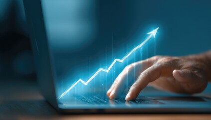Close-up of a hand hovering over a laptop, a glowing upward-trending graph projected onto the screen