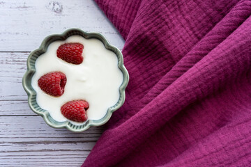 Green porcelain bowl and natural yogurt with berries on the stone marble table.