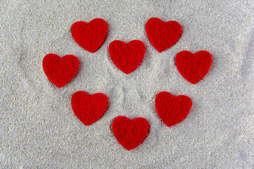 Red fabric hearts on the sea sand.