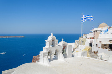 Greek Bell Tower and Flag Overlooking the Aegean Sea in Santorini, Greece