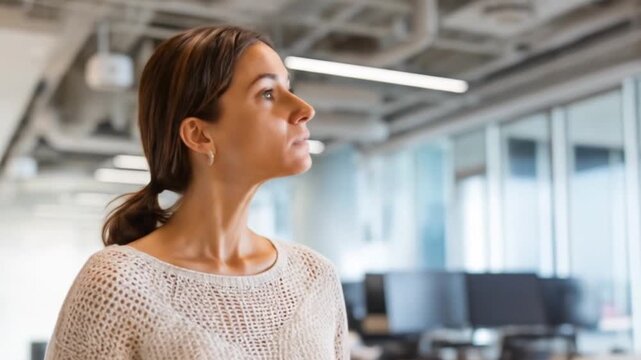 A modern office interior, featuring a woman observing a large display screen showing data visualizations.