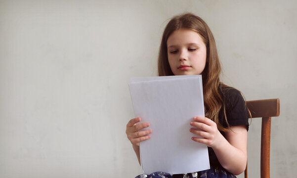 Girl with blank copyspace A4 sheet of paper, education, learning, studying. Teenager girl reading her film script during rehearsal in theatre on stage. Casting, audition. Place for text