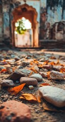 Ruined archway path, stones, autumn leaves.  Low angle view of a crumbling archway.  Colorful stones and orange leaves cover the path.  Sunlight streams through the opening