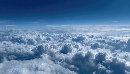 Expansive view of cumulus clouds from high altitude. A vast field of fluffy, white and grey clouds fills the entire image, stretching to the horizon. 