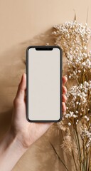 Hand holding a blank smartphone screen,  beige background,  floral elements