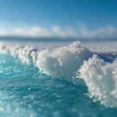 Close-up of snow crystals bordering a turquoise icy surface. Sunlight highlights the textures