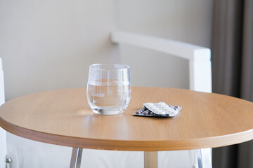 blisters with pills and glass of water on the table