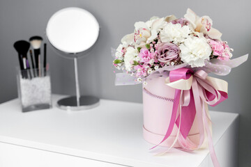 Beautiful flowers in a gift box stand on a dressing table. A gift for a beloved woman. Bouquet for a special event. International Women's Day. Concept of love
