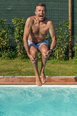 A man cannonball dives into the pool screaming