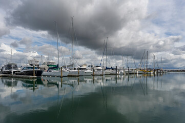 yachts in marina with moody sky and reflections