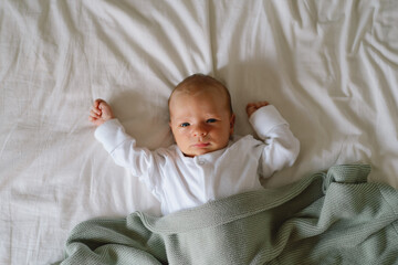 Newborn baby lying on bed under a soft blanket, capturing a moment of innocence and curiosity...