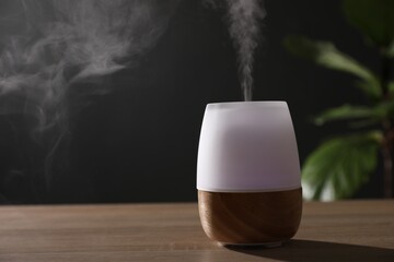 Modern aroma lamp on wooden table indoors. Space for text
