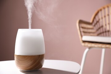One stylish aroma lamp on white table against pink wall, closeup. Space for text