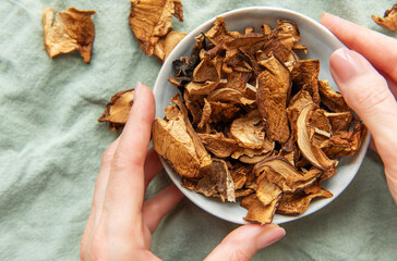 Chef holding bowl of dried mushrooms on green tablecloth