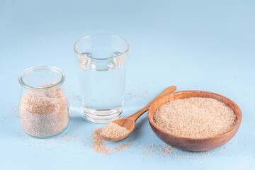 Whole Psyllium Husk in spoon, bowl and jar, with glass of water