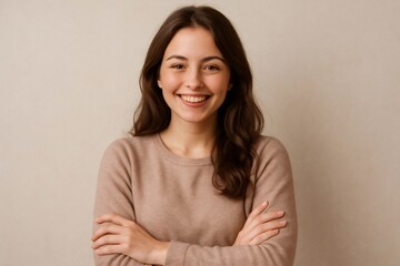 Obraz premium Confident woman smiling warmly with arms crossed, exuding positivity and friendliness against a neutral background. Ideal for business or lifestyle themes