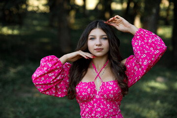 woman in pink dress and curly hair in forest on summer day